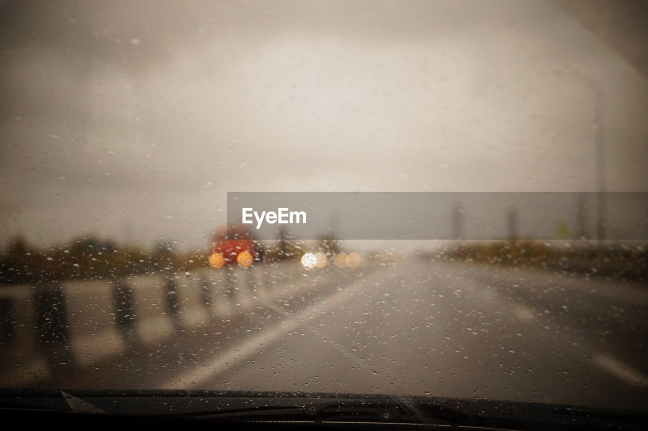 Road seen through wet car windshield during rainy season