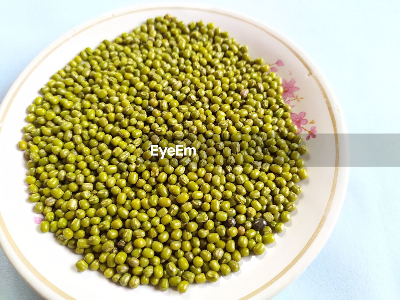 Green mung beans on plate, white background.