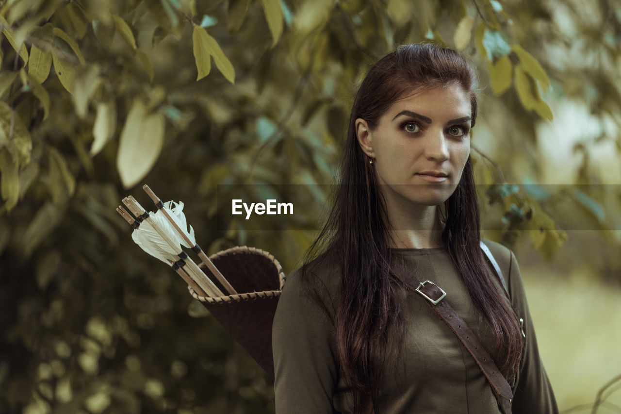 Portrait of female archer standing on field