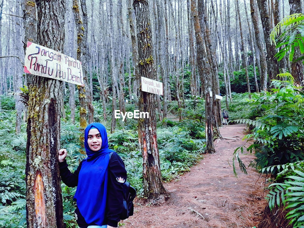 Portrait of woman standing by tree in forest