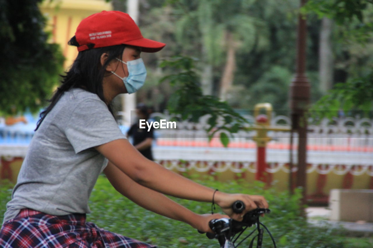 SIDE VIEW OF WOMAN RIDING BICYCLE ON ROAD