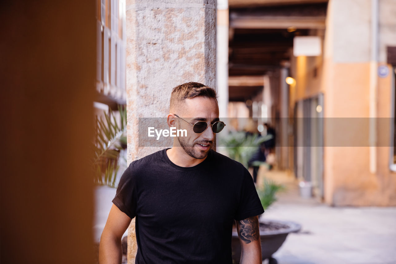 Man wearing sunglasses while standing against columns