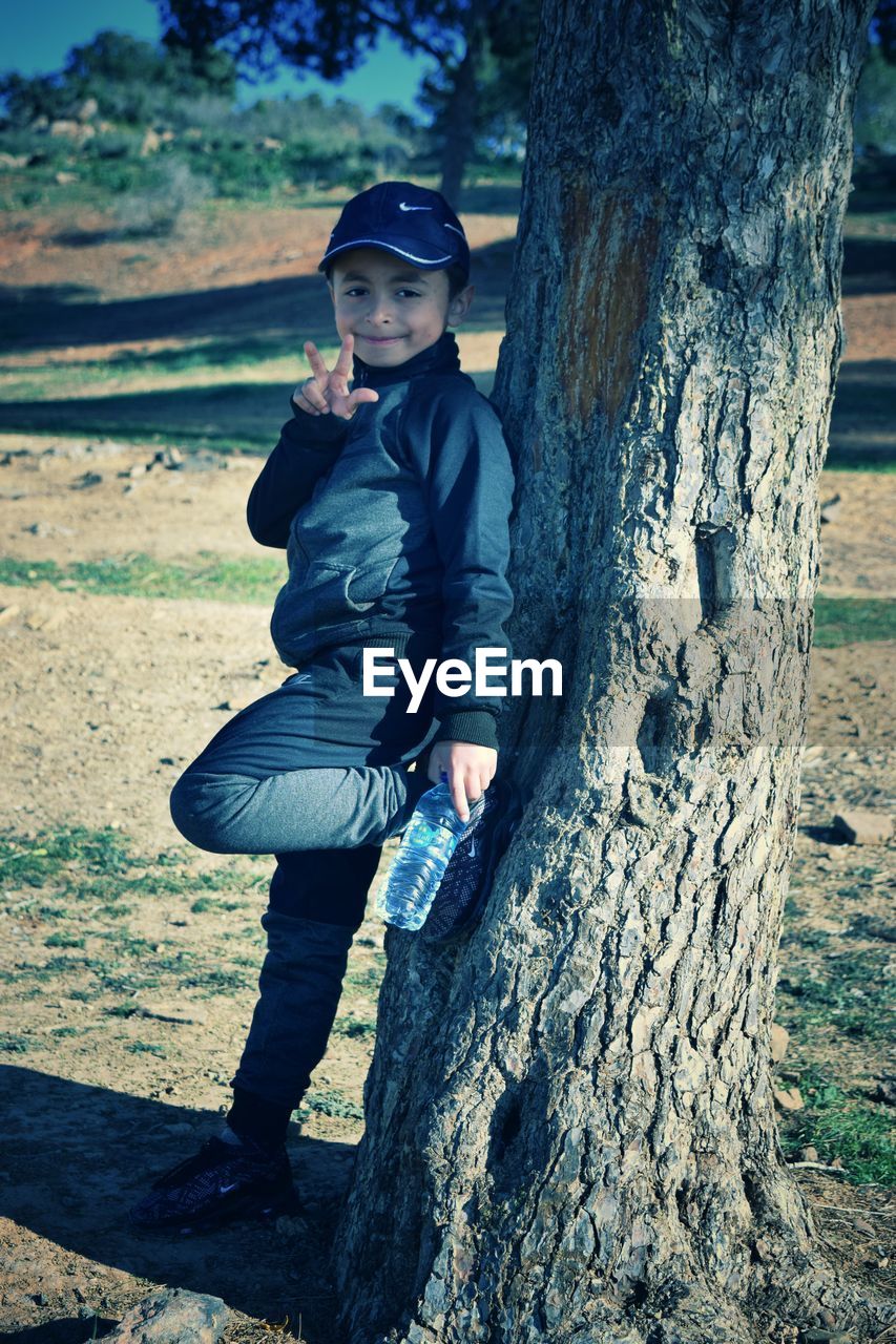 FULL LENGTH OF BOY WITH TREE TRUNK