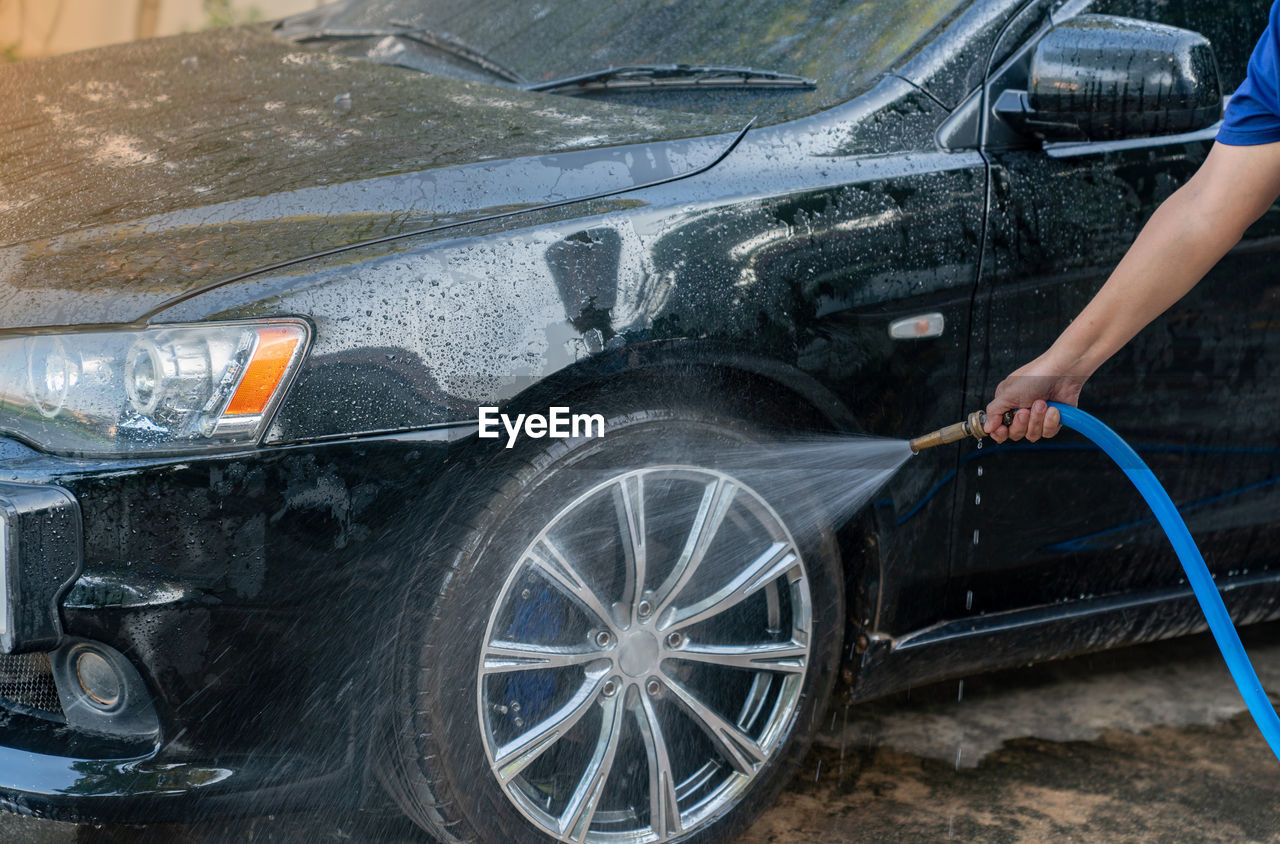 Woman washing her car at home.car wash self-service.