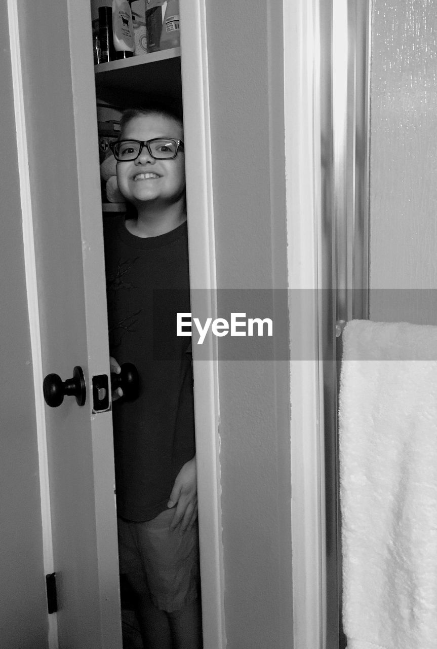 PORTRAIT OF BOY STANDING AT ENTRANCE OF OPEN DOOR