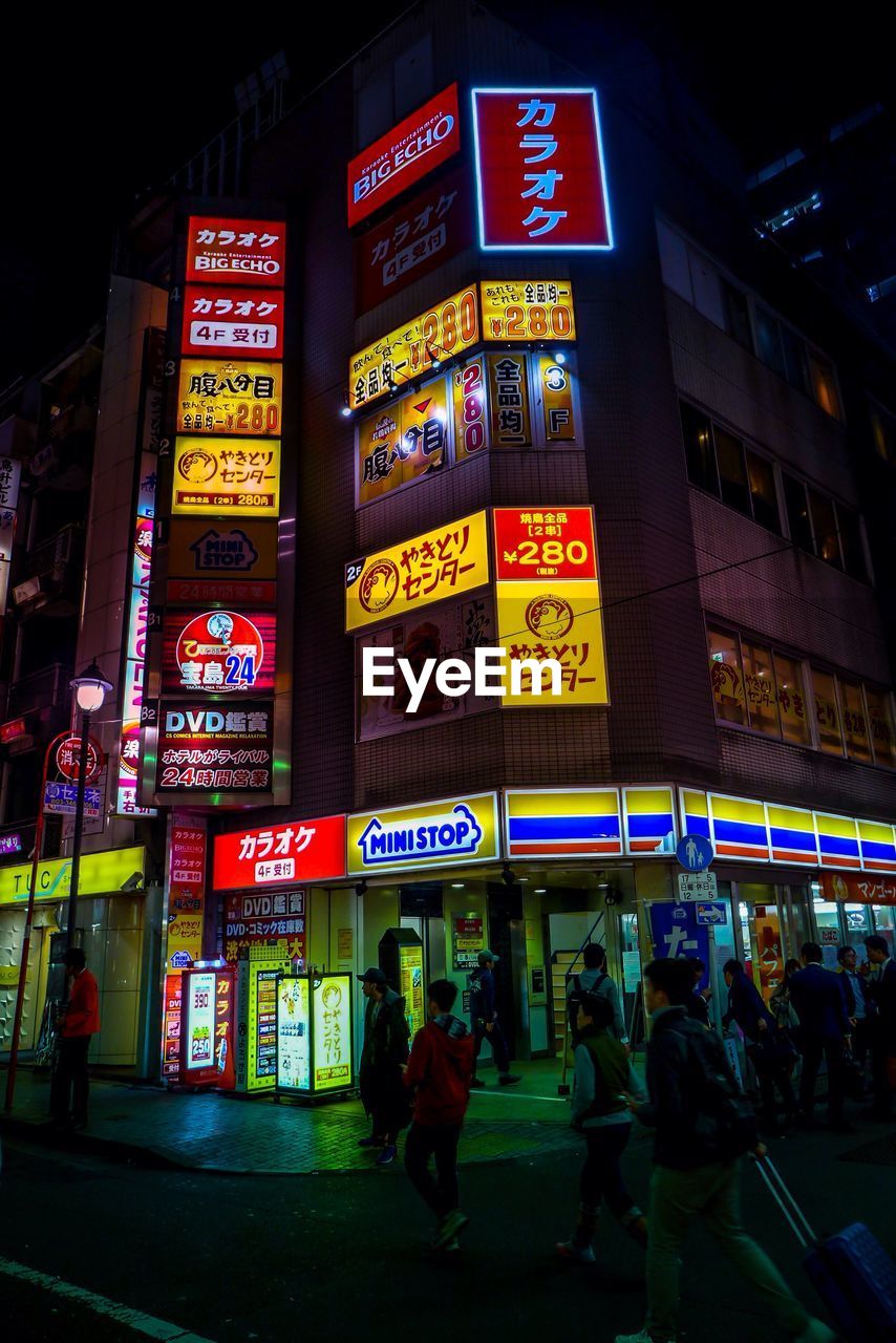 PEOPLE ON ILLUMINATED STREET AT NIGHT