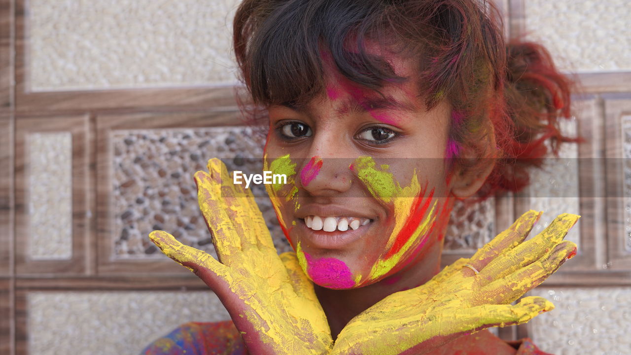 Beautiful young girl posing with exploding pink and yellow holi powder around her