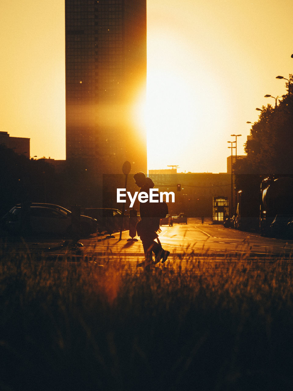 SILHOUETTE MAN ON STREET IN CITY AGAINST SKY DURING SUNSET
