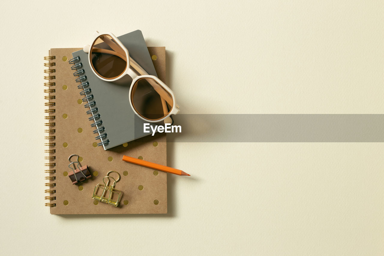 High angle view of sunglasses and binder clips on note pads