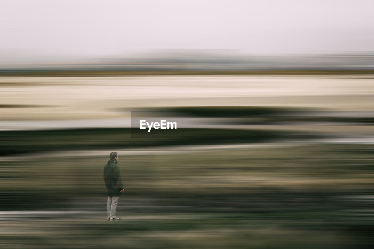 Blurred motion of man walking on road