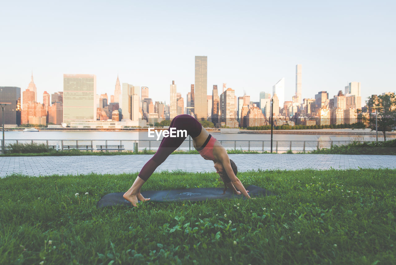 WOMAN LOOKING AT CITYSCAPE AGAINST SKY