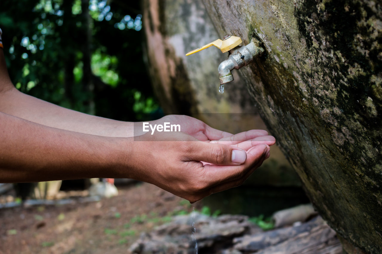 Cropped image of man with hands cupped on faucet