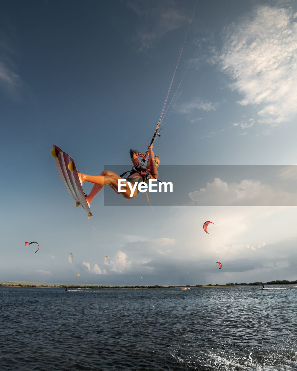 Professional athlete kitesurfer young caucasian woman doing a trick in the air against the backdrop 