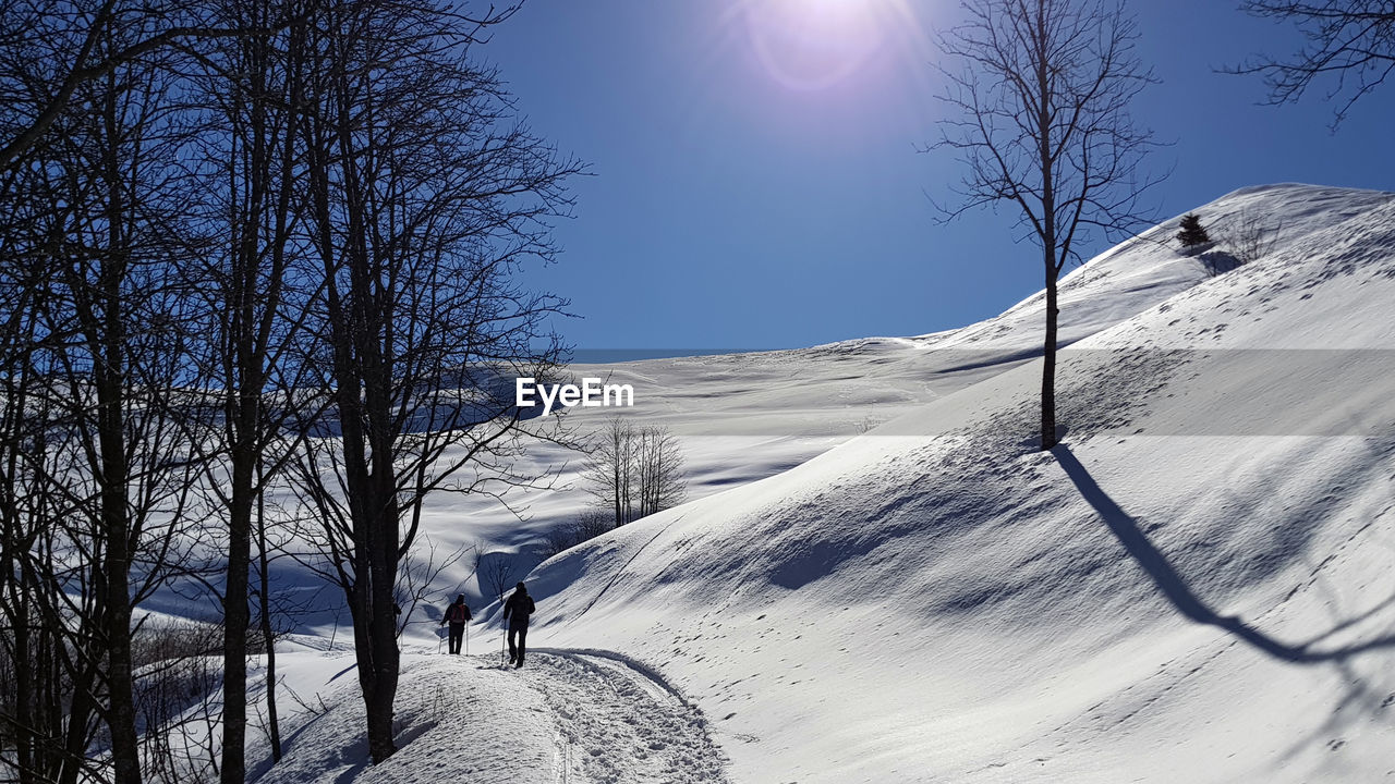 People hiking on snow covered mountain against sky