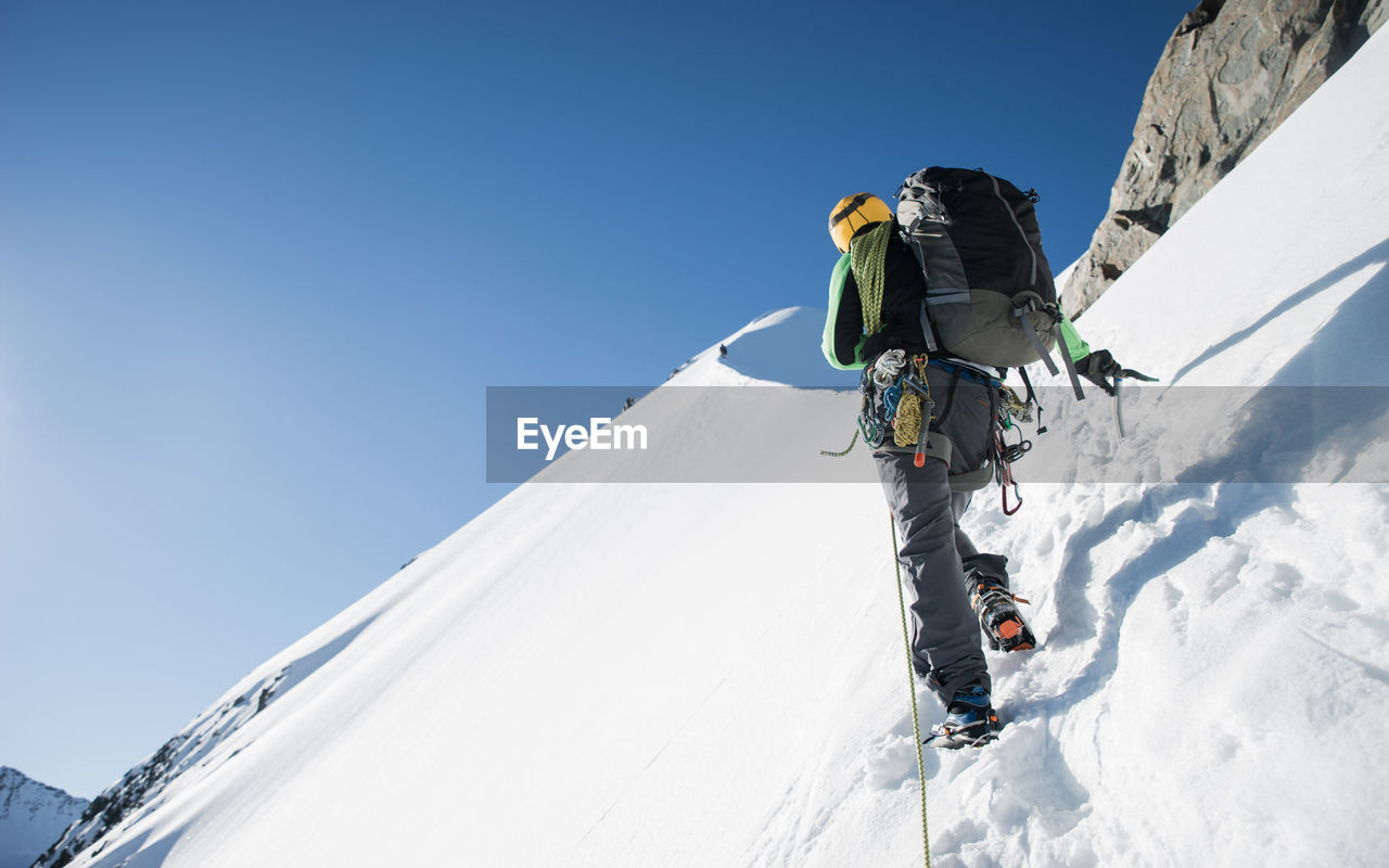 Man hiking on snowcapped mountain on sunny day