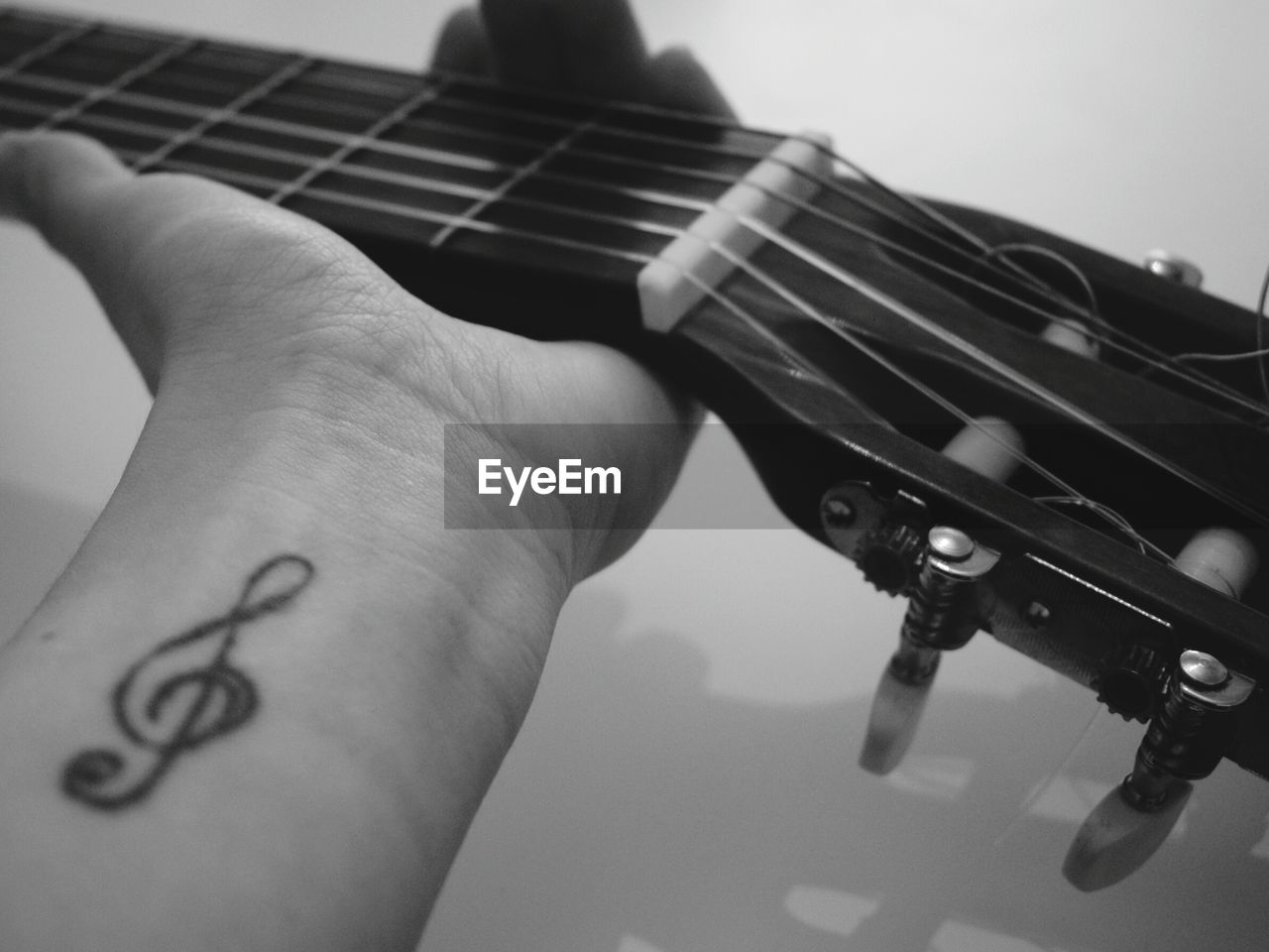 Close-up of hand with tattoo holding guitar