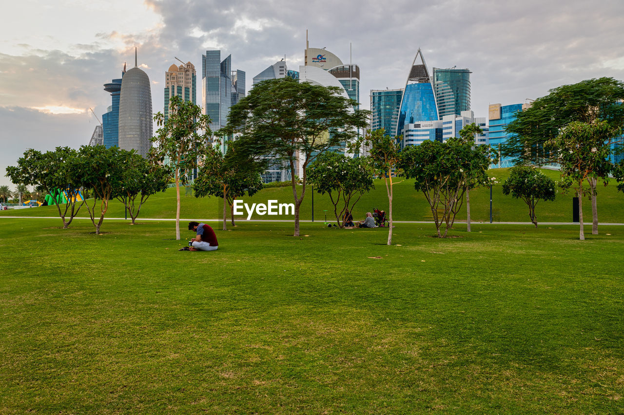 TREES AND BUILDINGS IN PARK AGAINST SKY