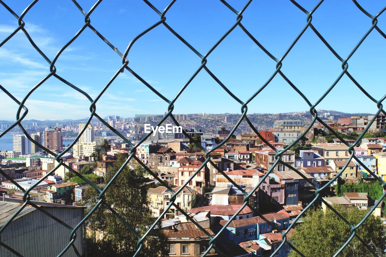 High angle view of cityscape seen through chainlink fence