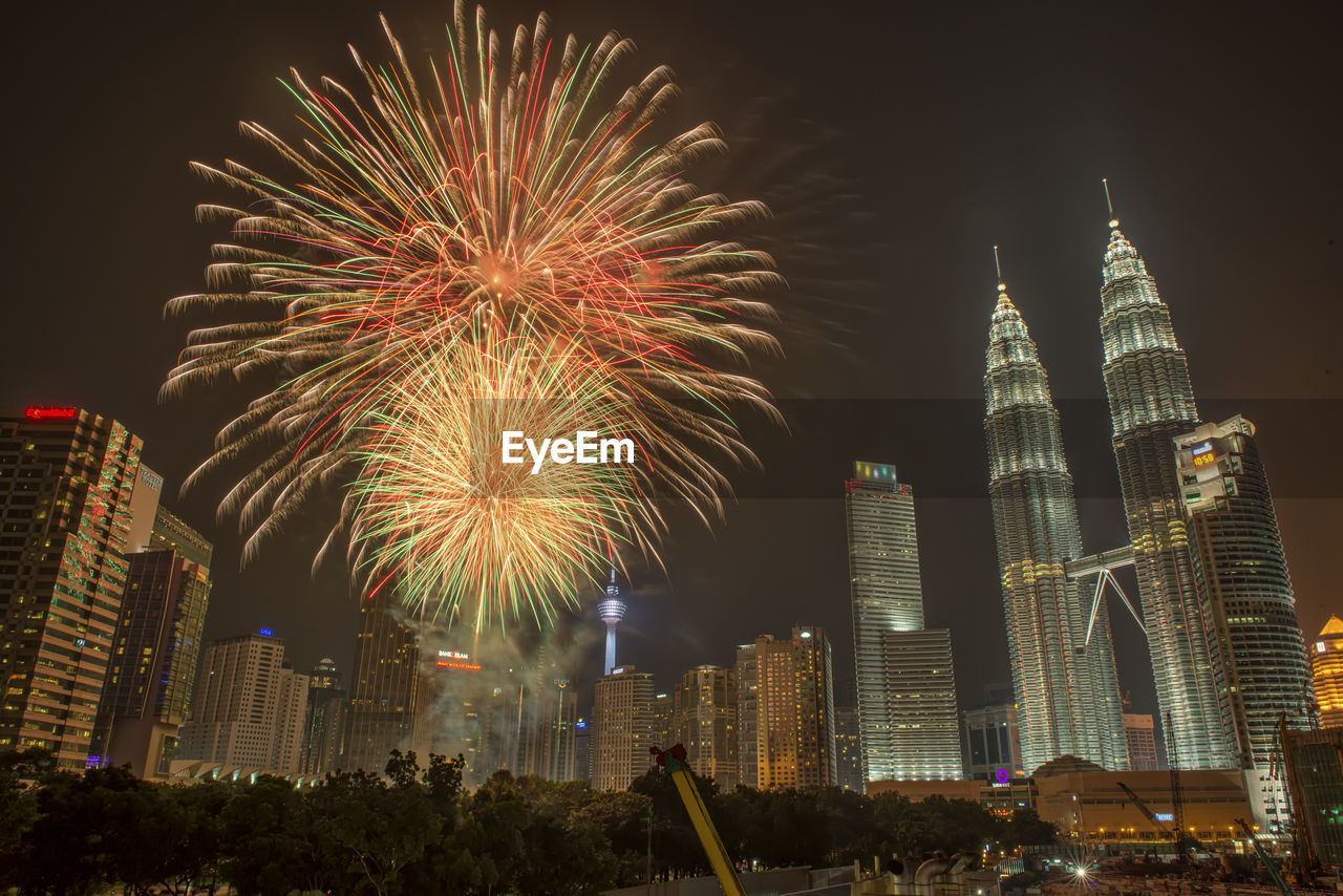 LOW ANGLE VIEW OF FIREWORK DISPLAY OVER CITY