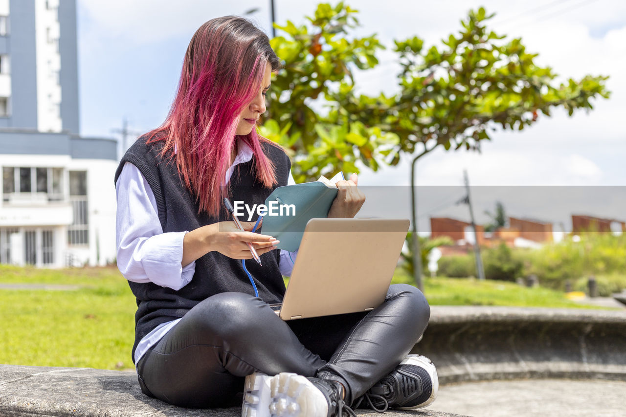 Young woman using mobile phone while sitting outdoors