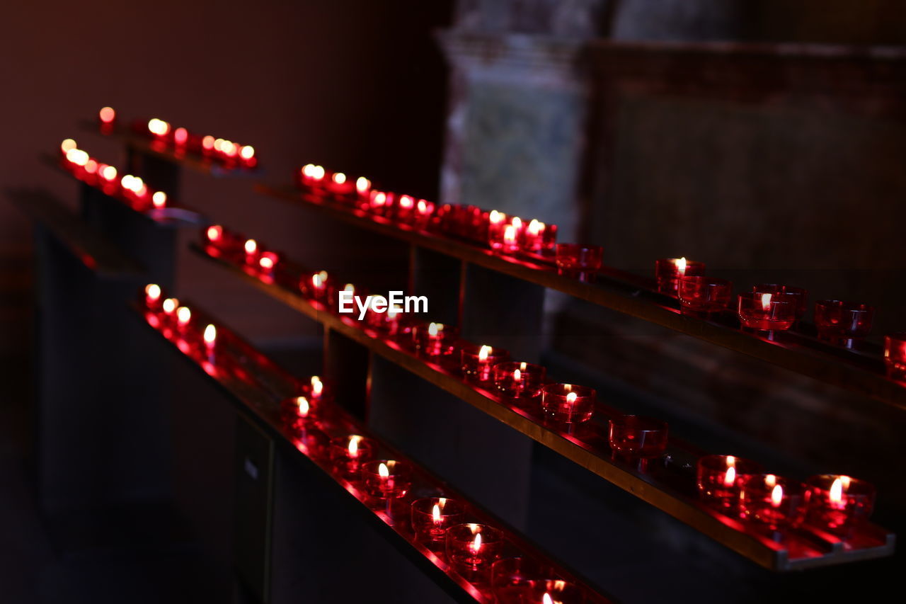 High angle view of red lit tea light candles in church