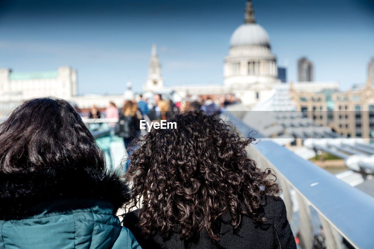 Rear view of women on london millennium footbridge against st paul cathedral