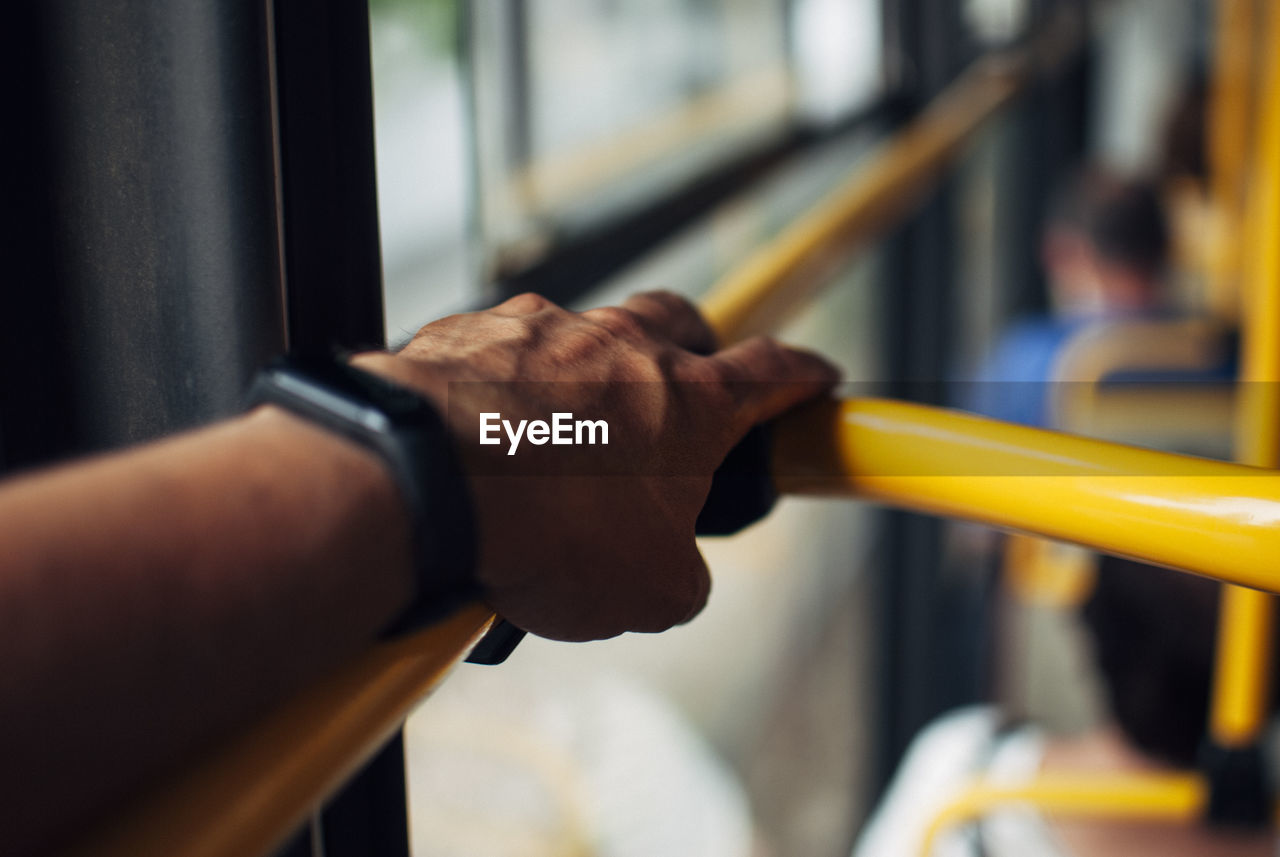 CLOSE-UP OF MAN HOLDING HAND ON METAL