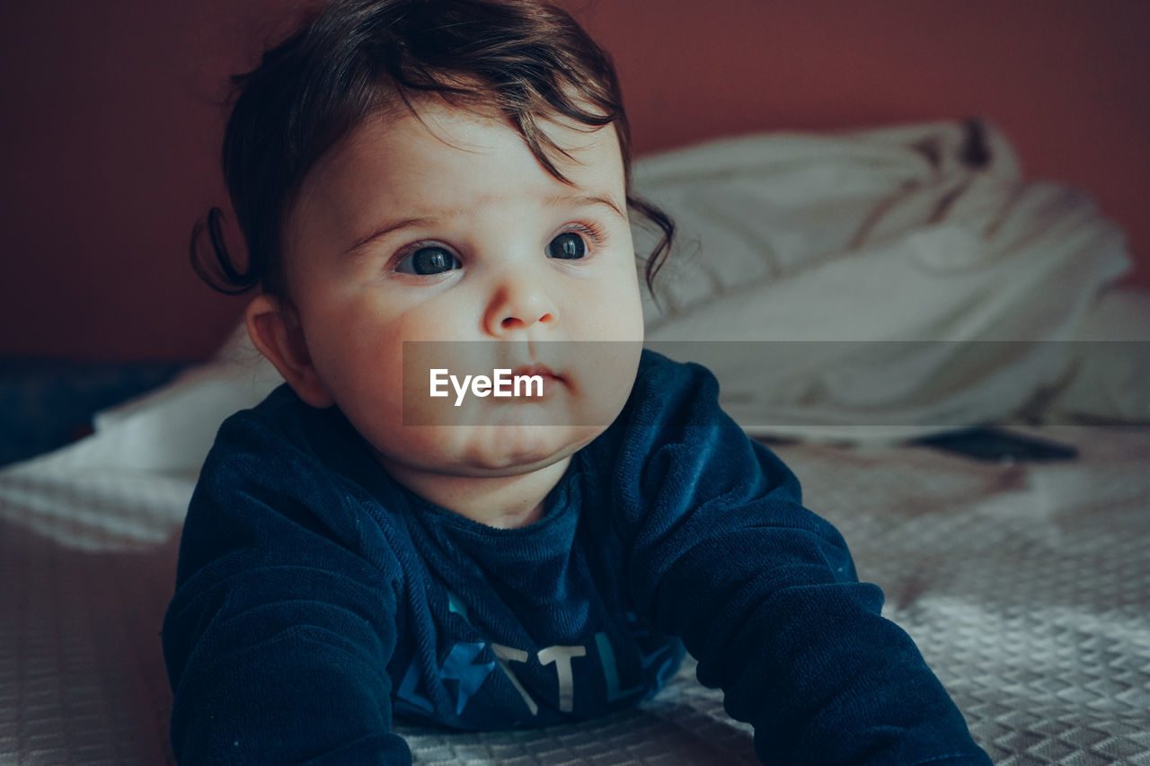 Cute baby girl on bed at home