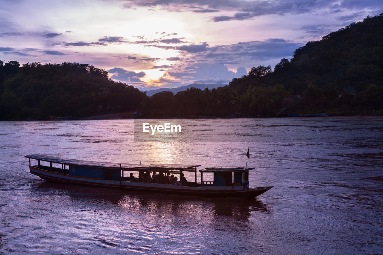 Small tour boat cruises along mekong river in luang prabang, laos