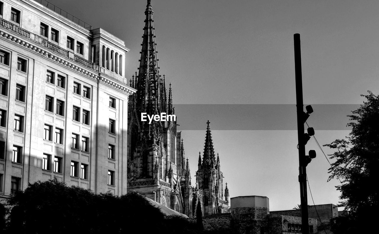 LOW ANGLE VIEW OF BUILDINGS AND TREES AGAINST SKY