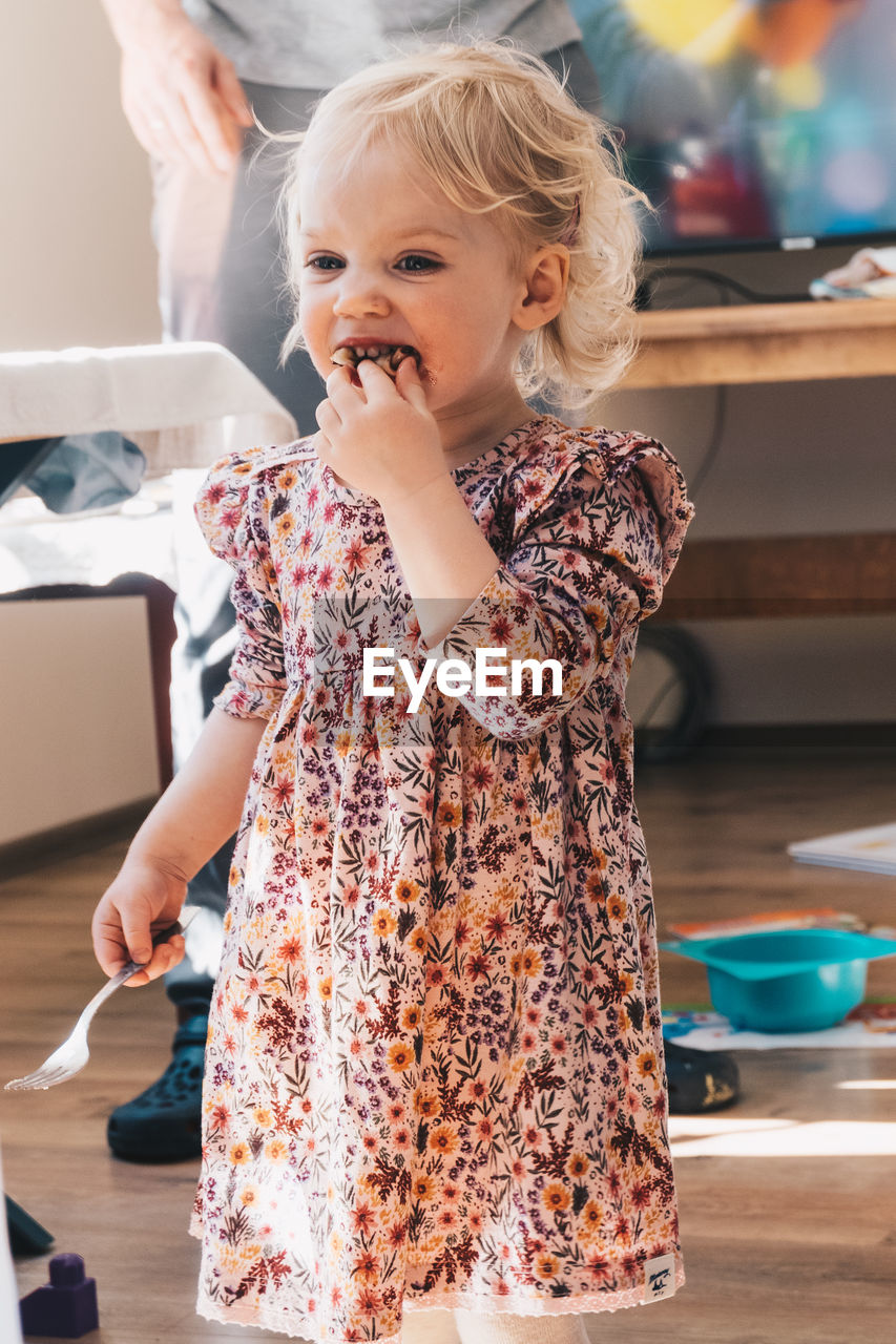 Baby girl looking away while standing at home