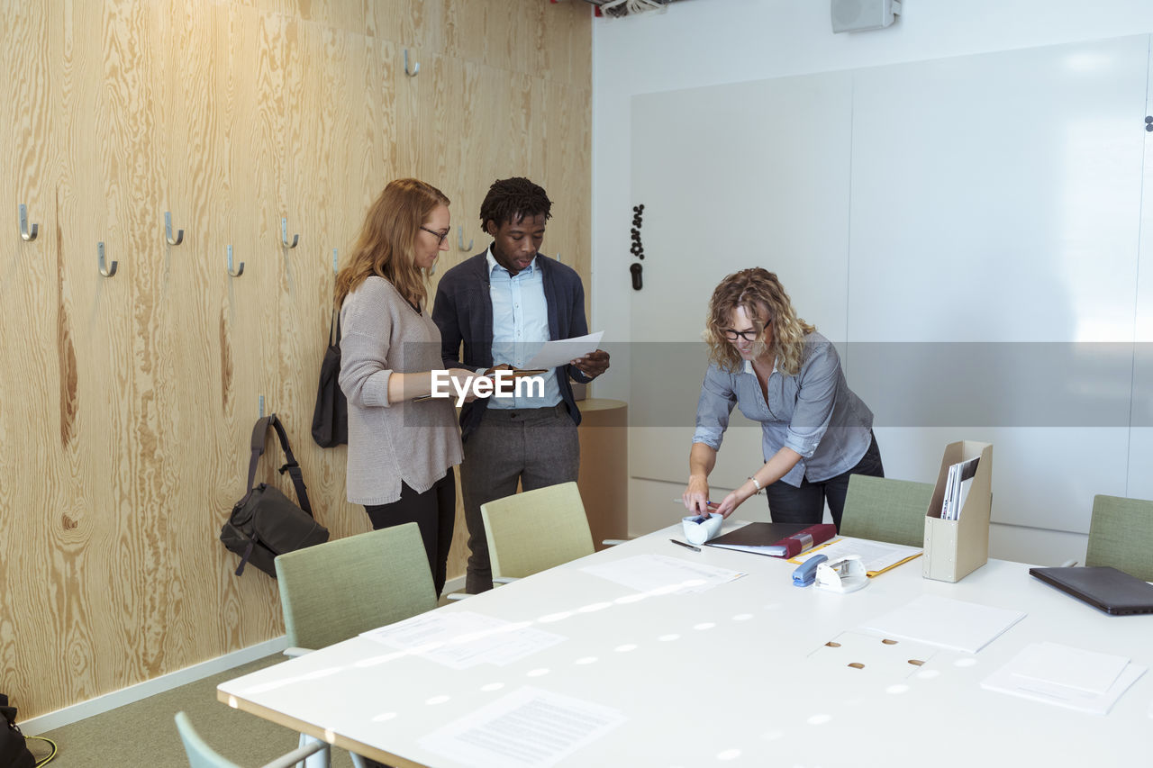 Male and female professionals working in board room at office