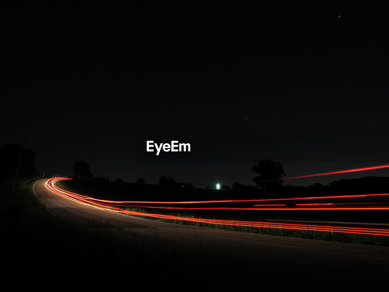 Light trails on road against sky at night