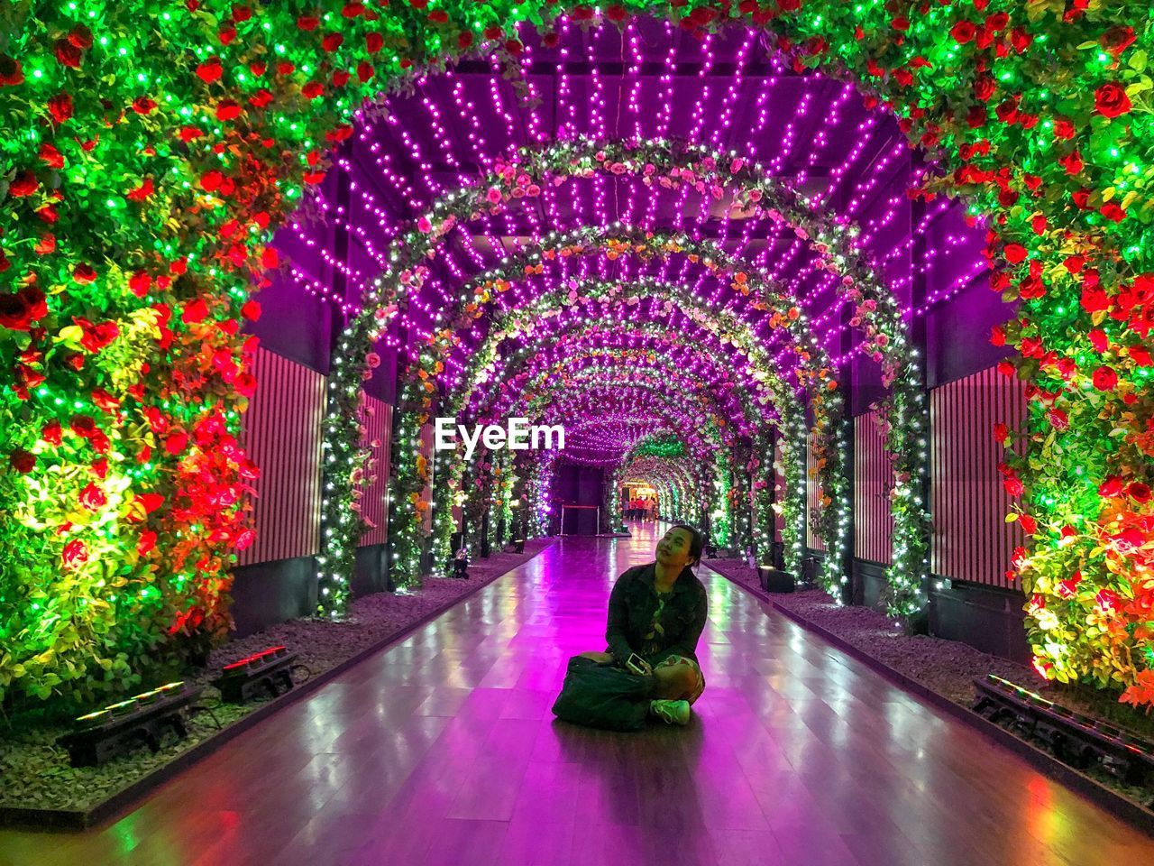 REAR VIEW OF WOMAN STANDING BY MULTI COLORED ILLUMINATED ARCHWAY