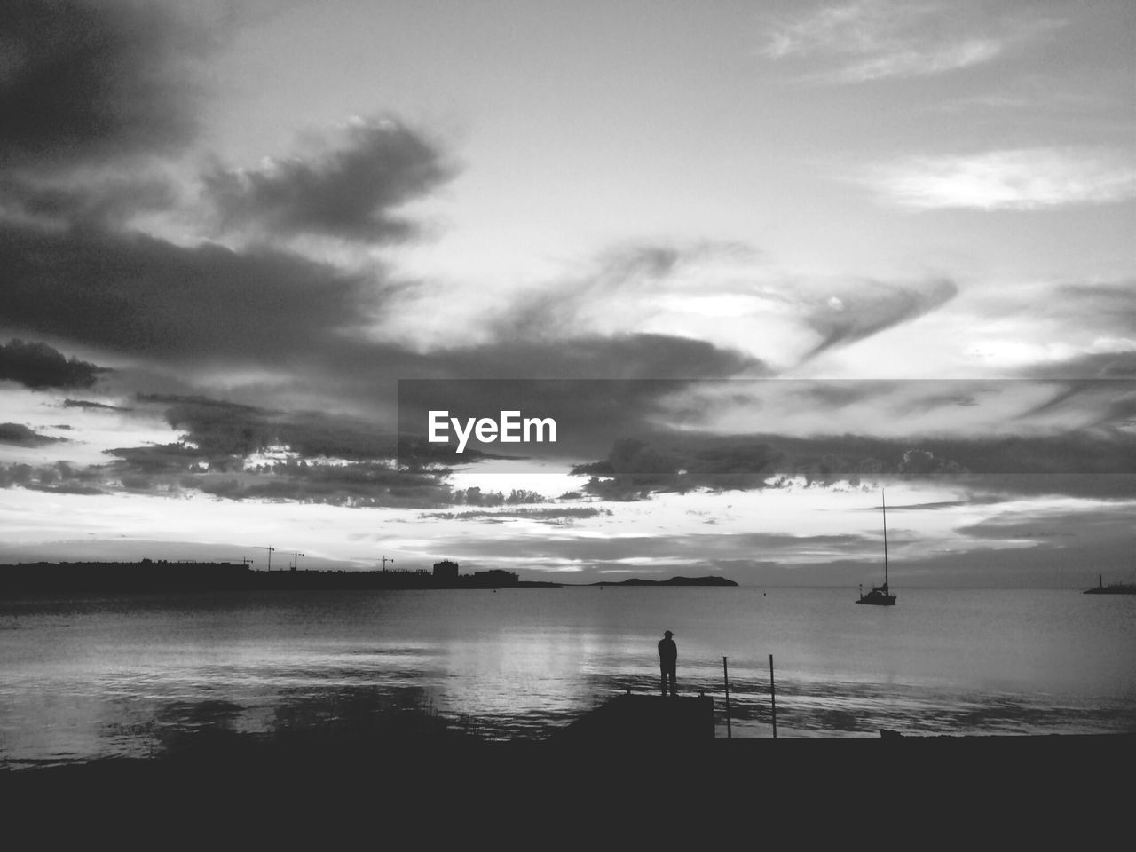 Rear view of a silhouette man overlooking calm sea