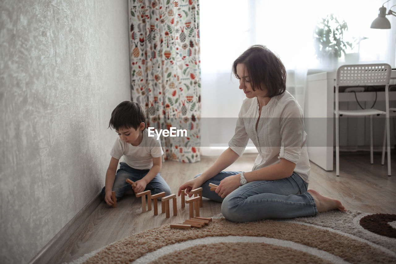 Joint game of mom and son at home, build houses from a wooden constructor. concept childhood 