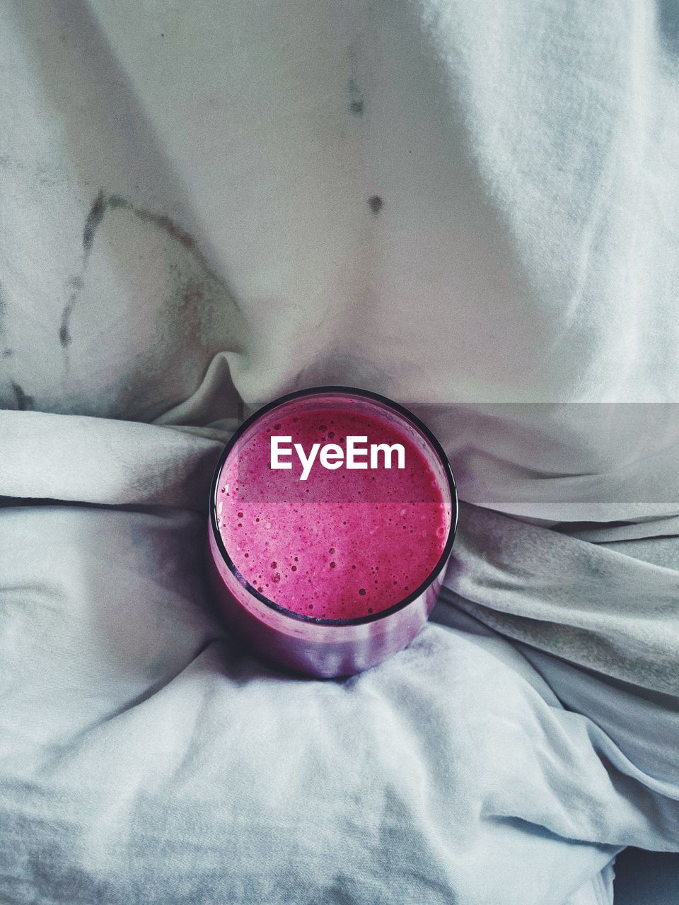 Close-up of a pink smoothie in bed