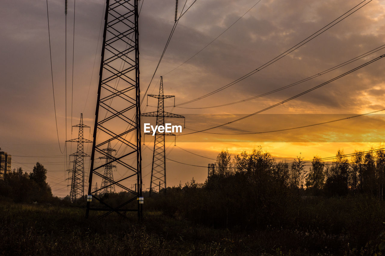 Silhouette electricity pylon against orange sky