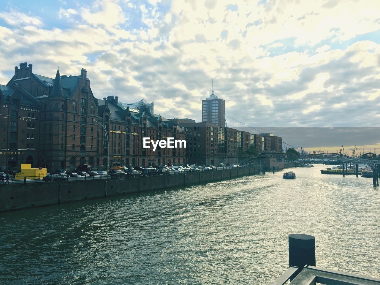 City at waterfront against cloudy sky