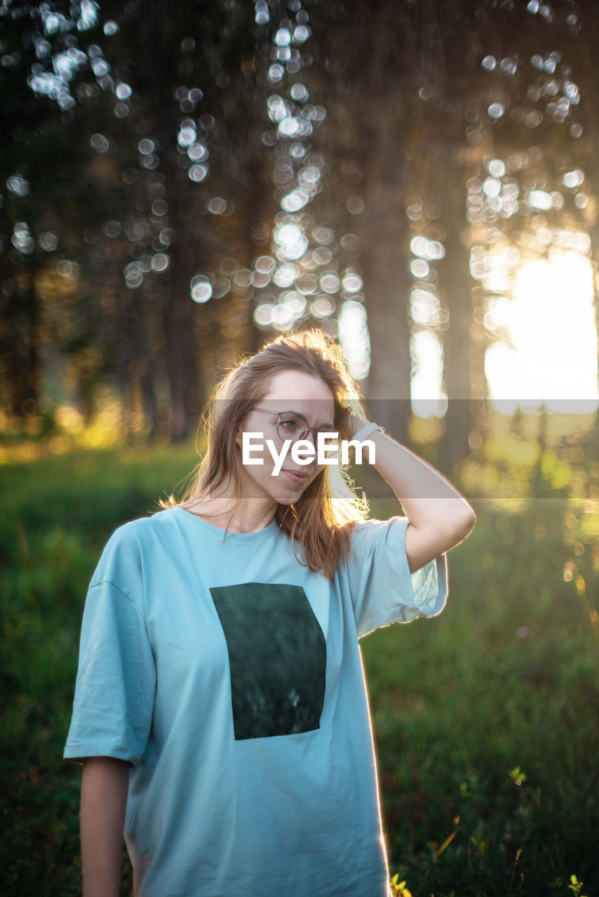 Happy woman standing by tree in forest