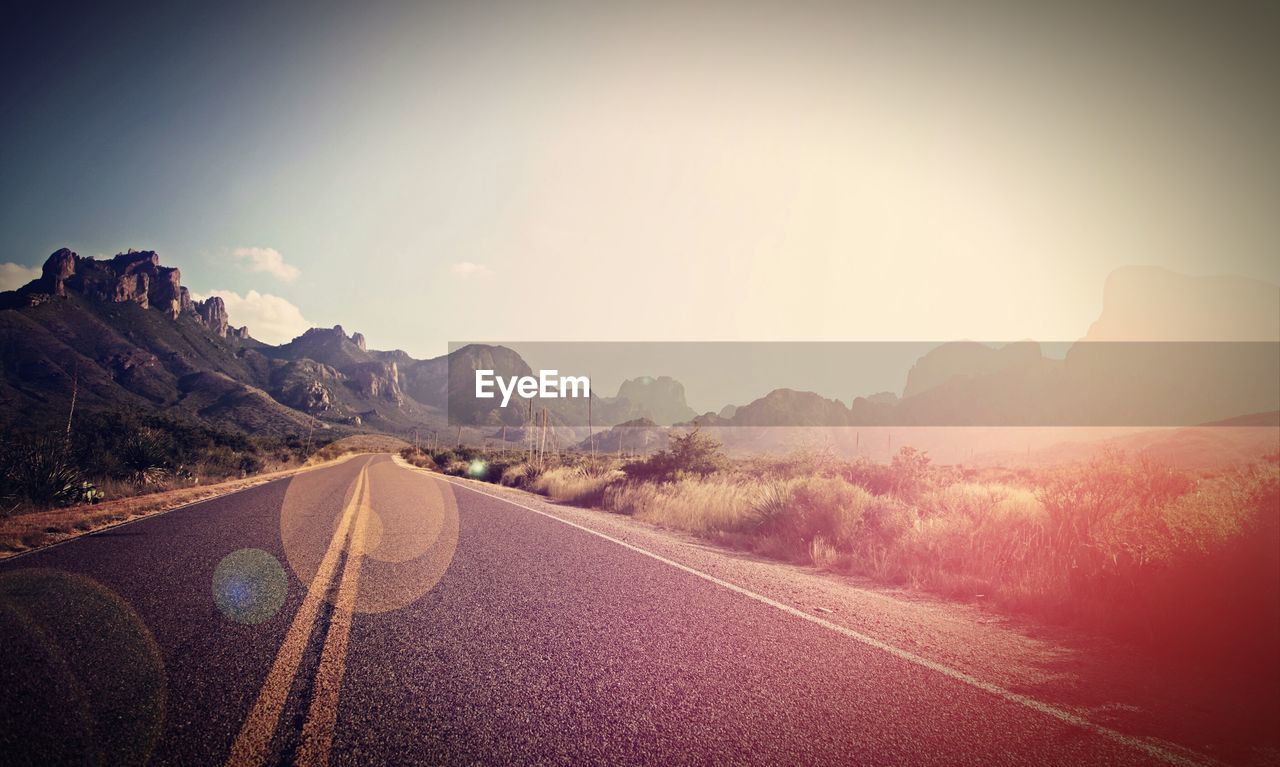 Empty road leading towards mountains against sky