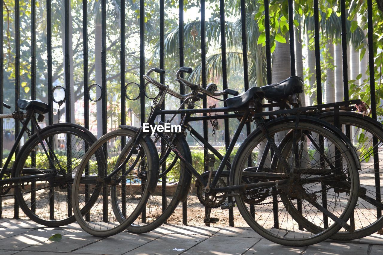 Bicycles parked on sidewalk by fence