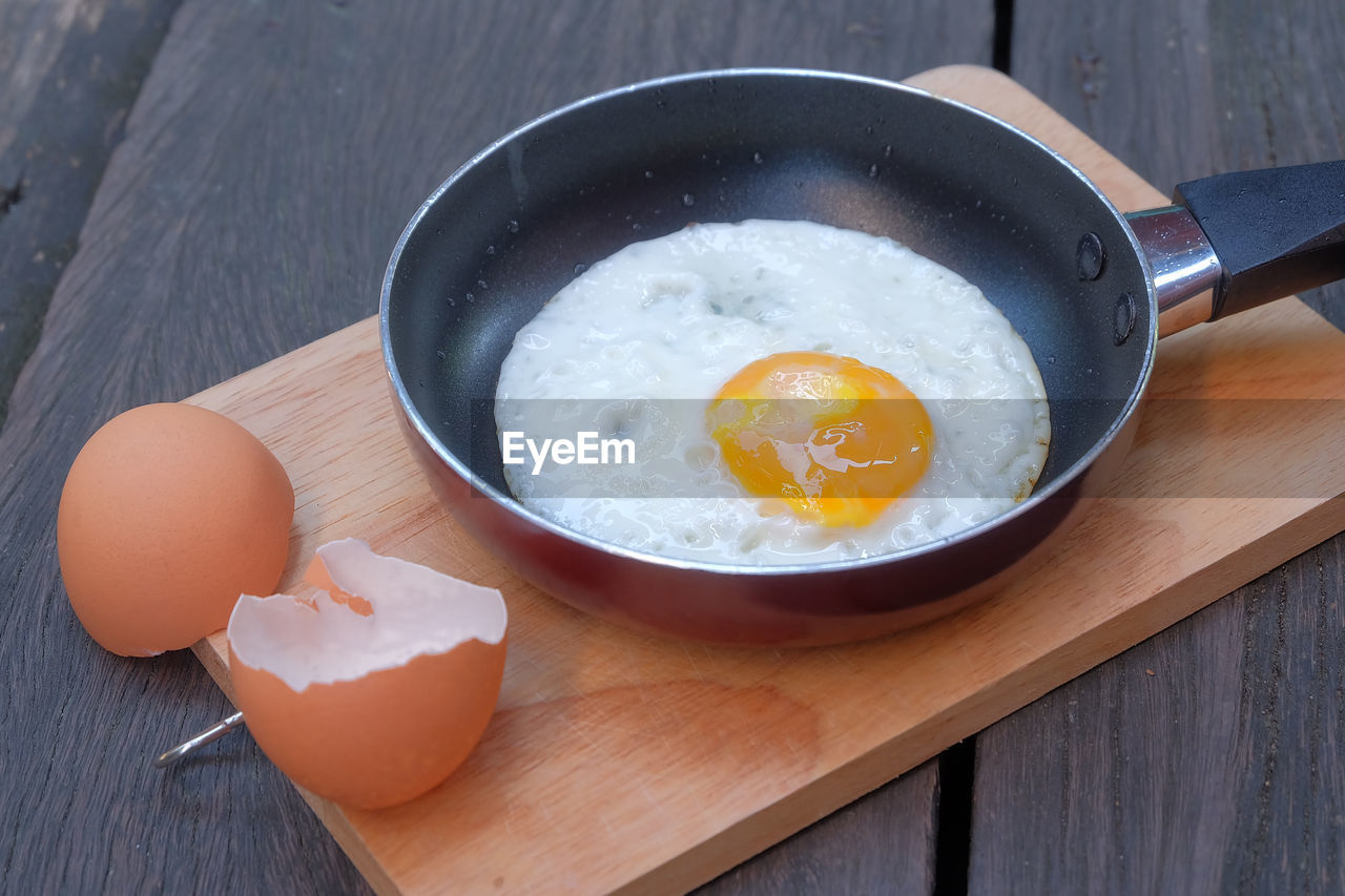 High angle view of egg in cooking pan on cutting board