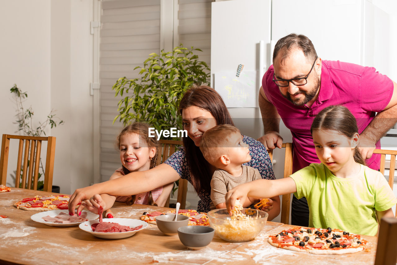 Cheerful kids preparing food with parent at home