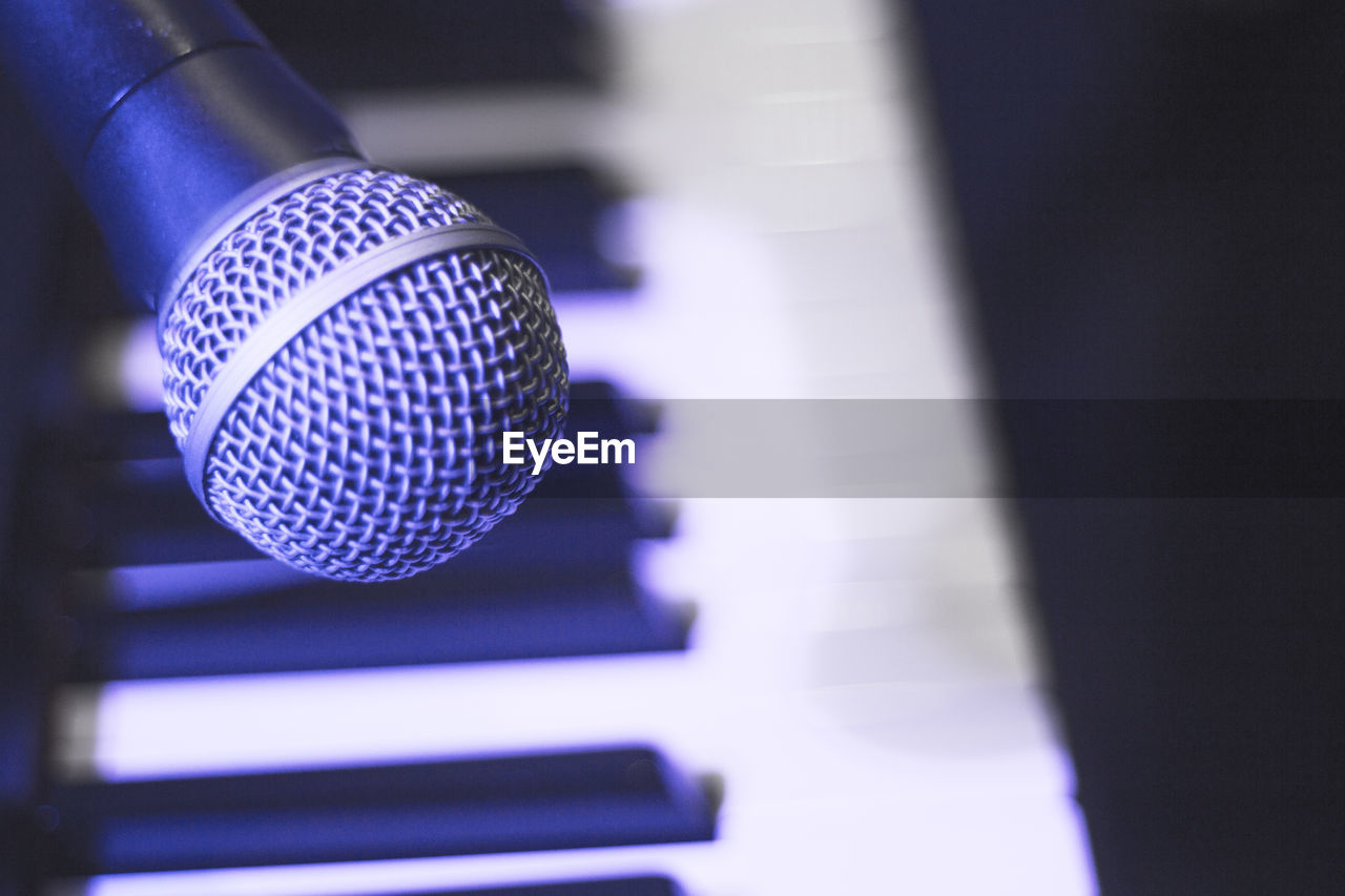 Microphone over piano keys in dim light. no people