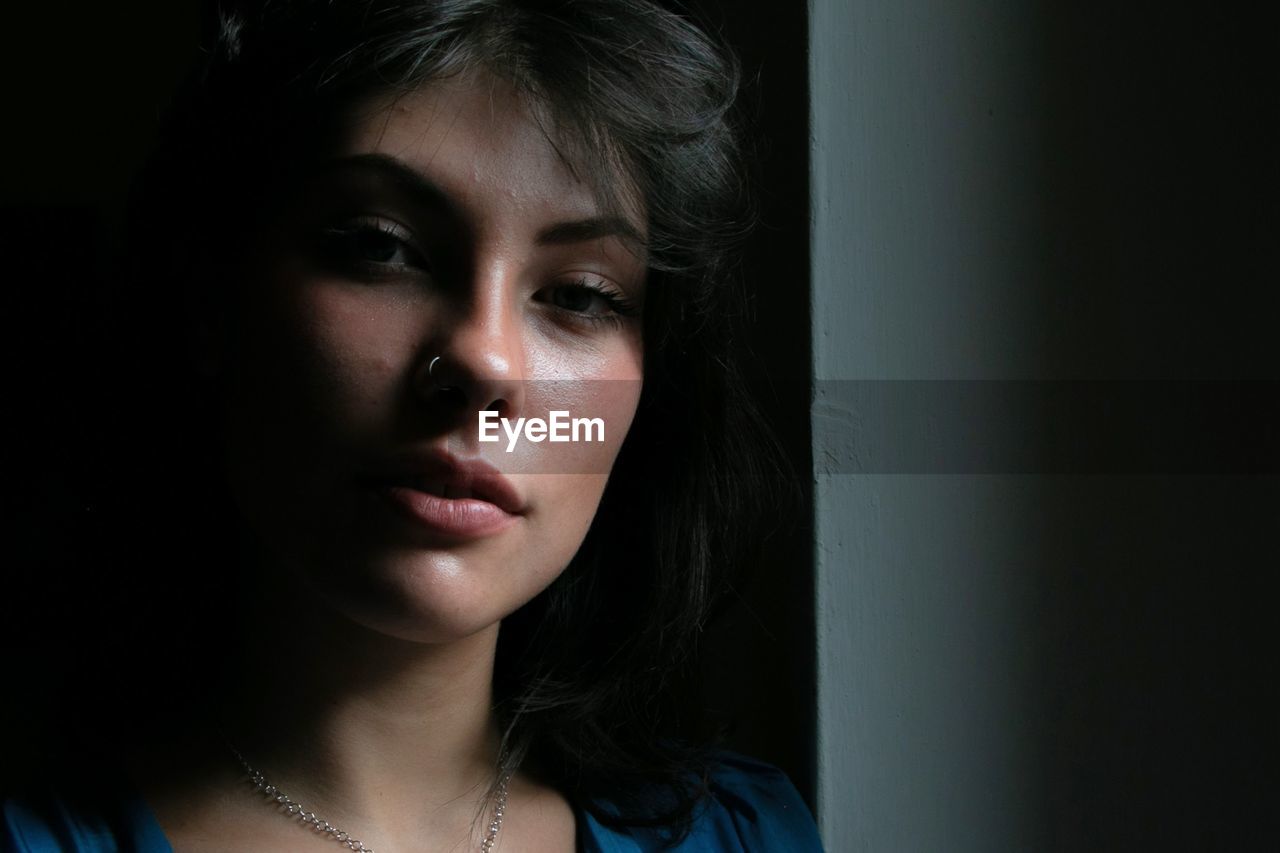 Close-up portrait of young woman against black background