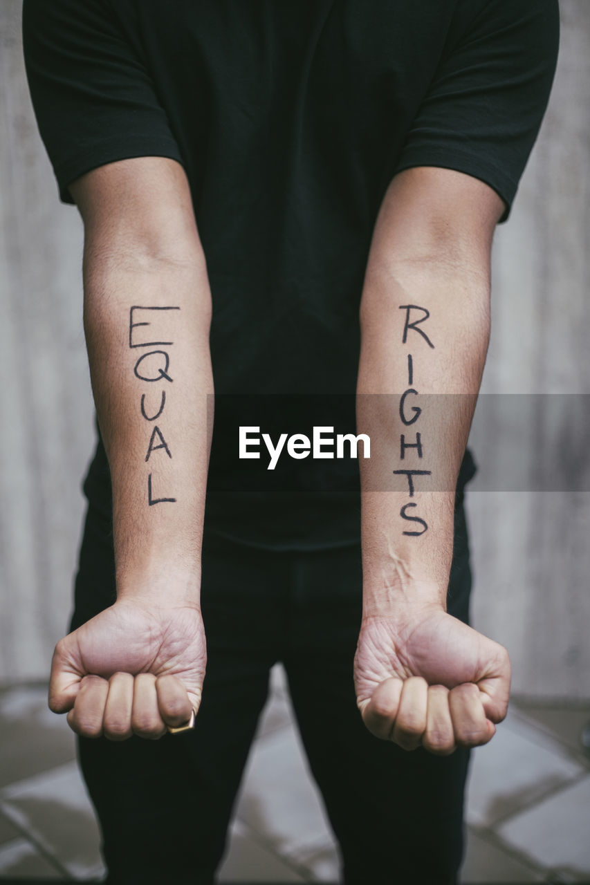 Midsection of male protestor showing equal rights written on hand