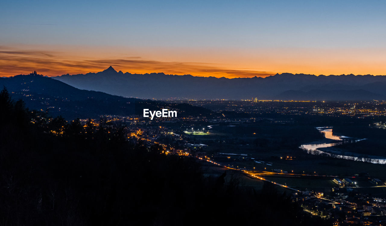 High angle shot of illuminated cityscape against sky during sunset