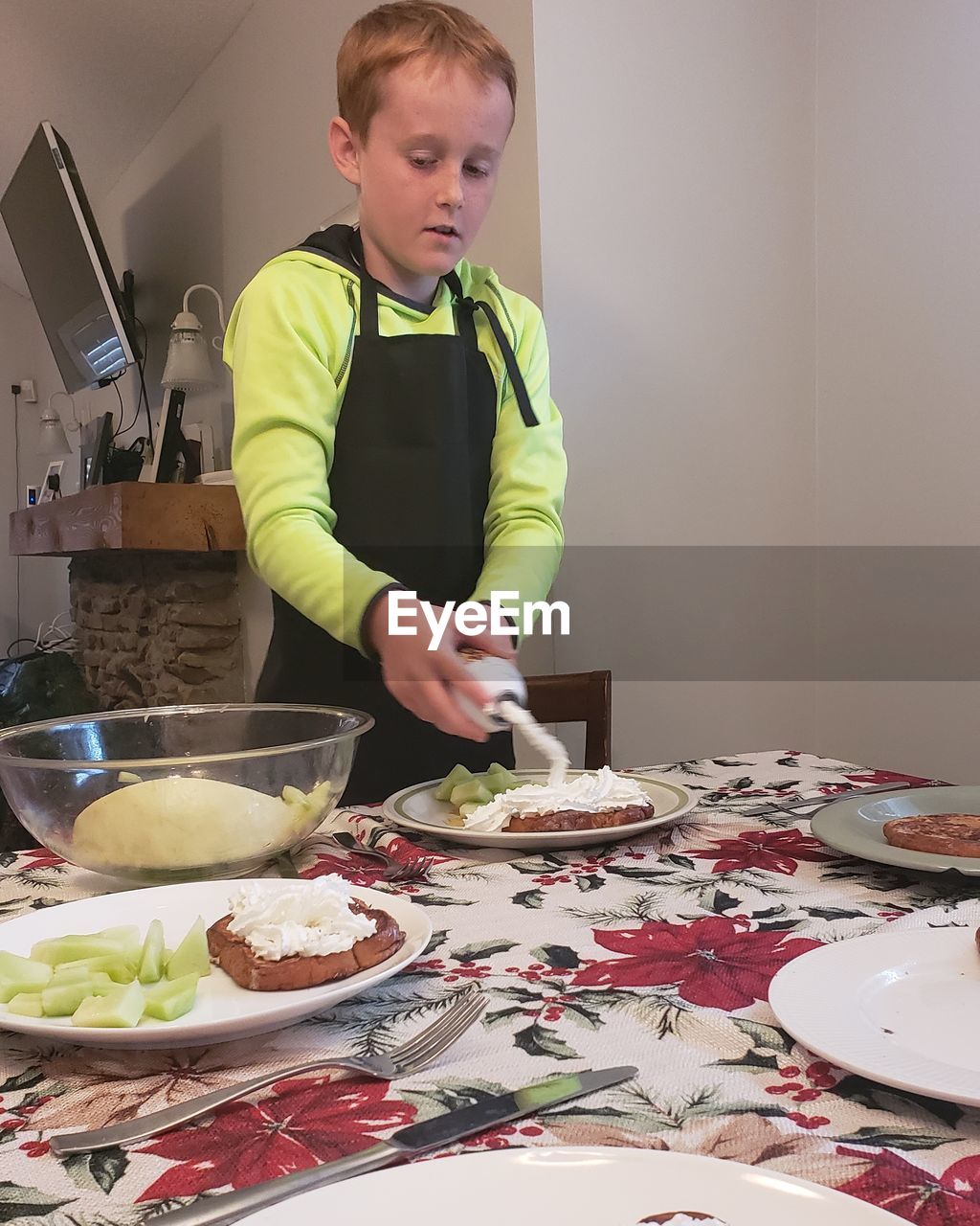 BOY STANDING ON TABLE AT HOME IN KITCHEN