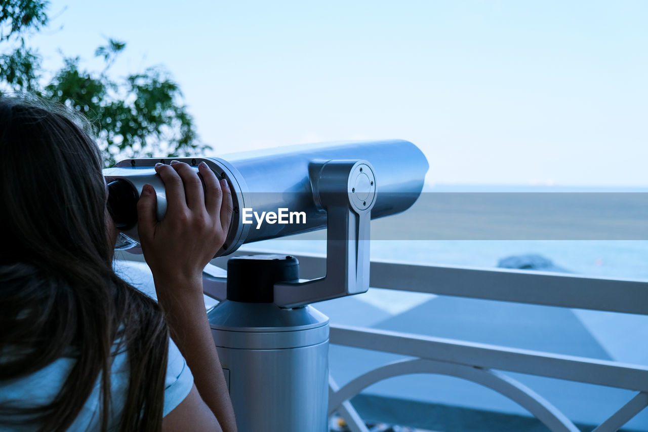 Woman looks through binoculars at the sea. traveler vacation holiday concept. new travel destination